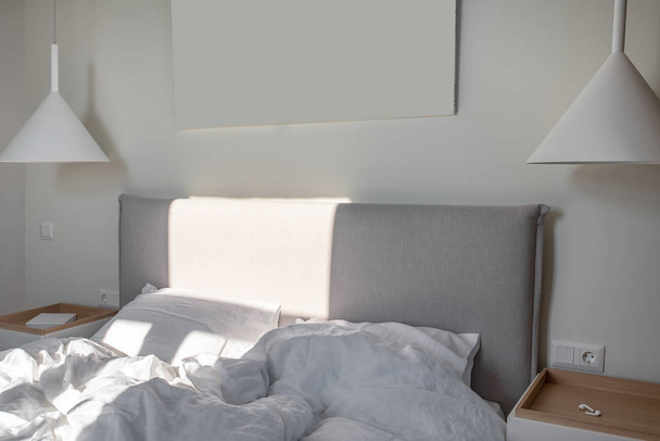 Ηλιόλουστο σύγχρονη κρεβατοκάμαρα με λευκούς τοίχους και κρεμαστά φωτιστικά - Φωτογραφία, εικόνα
