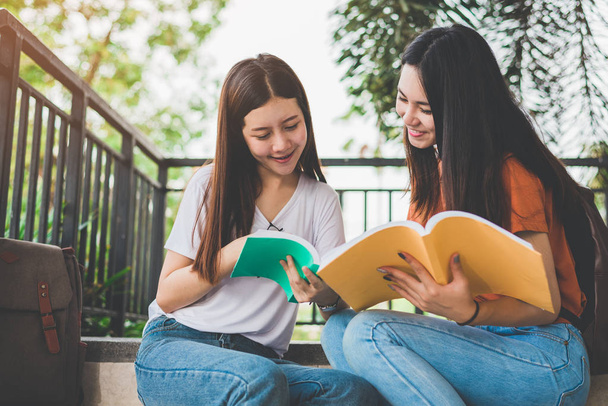 zwei asiatische Schönheitsmädchen, die gemeinsam Bücher für die Abschlussprüfung lesen und betreuen. Student lächelt und sitzt auf der Treppe. Bildung und zurück zum Schulkonzept. Lebensstile und Menschen Portrait Thema. - Foto, Bild