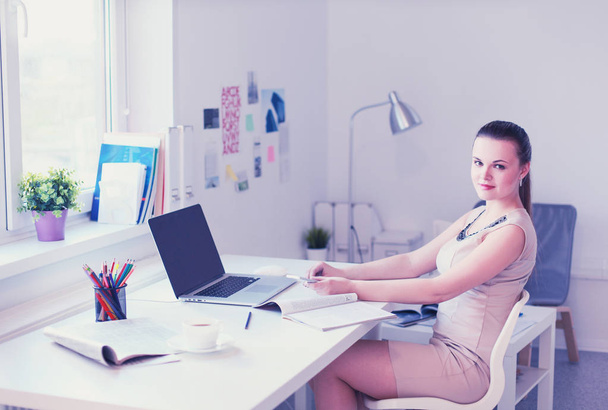 Beautiful business woman working at her desk with headset and laptop - Fotografie, Obrázek