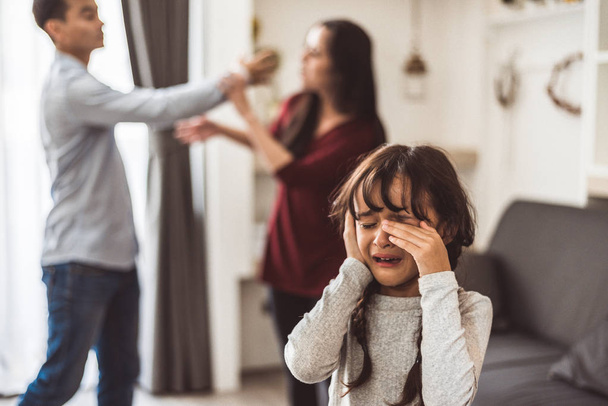 Little girl crying because of her parents quarreling. Girl abused with mother and father shouting and conflict angry background in home. Family dramatic scene, Family social issues problem concept. - Fotó, kép
