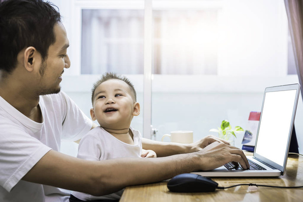 Egy apa és fia használ laptop együtt boldogan. Technológia és az életmód fogalmát. Boldog familly és a baba-téma. - Fotó, kép