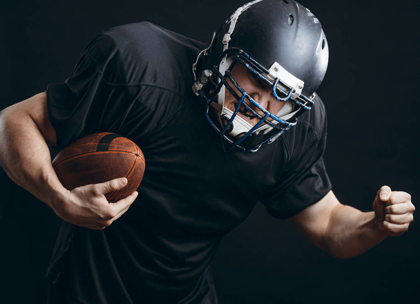 American football sportsman player in action isolated over black studio wall - Foto, Bild