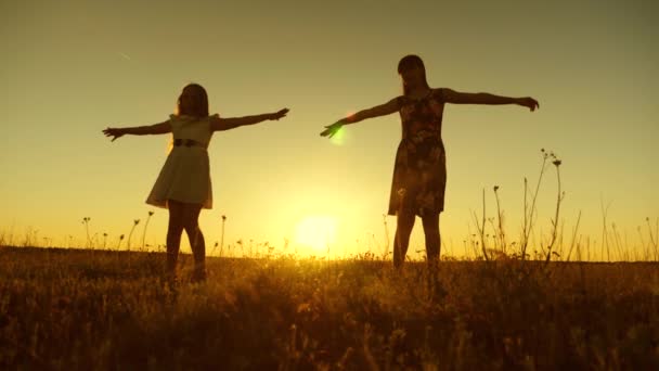 Boldog tizenéves lányok az örvénylő, napnyugtakor a arany nap. Lassú mozgás. - Felvétel, videó