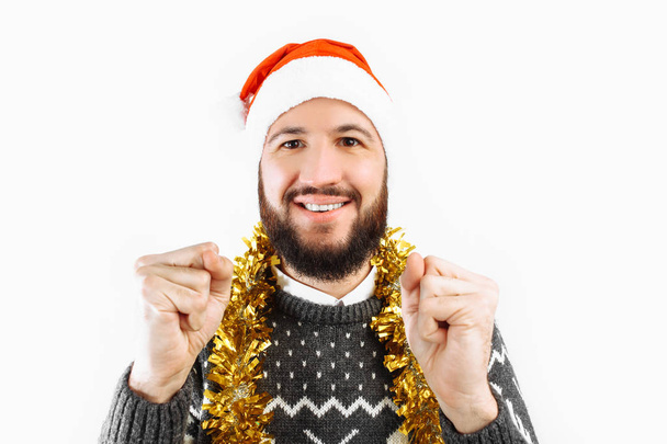 A man with a beard in a Santa Claus hat holding Christmas balls, Christmas-tree decorations, on a white background. - Foto, Imagen