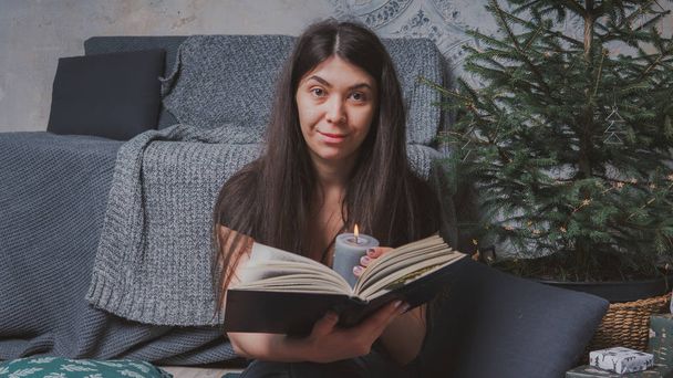 Student reading a book in a cozy room. Girl holding a book. Concept: reading a book - Valokuva, kuva