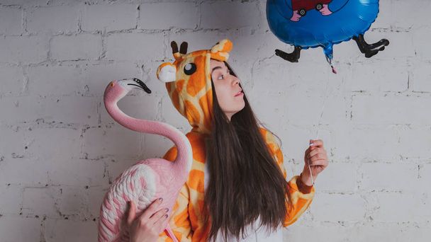 pajamas in the form of a giraffe. emotional portrait of a girl on a gray background. crazy and funny man in a suit. clean skin and long hair. animator for children's parties - Photo, image