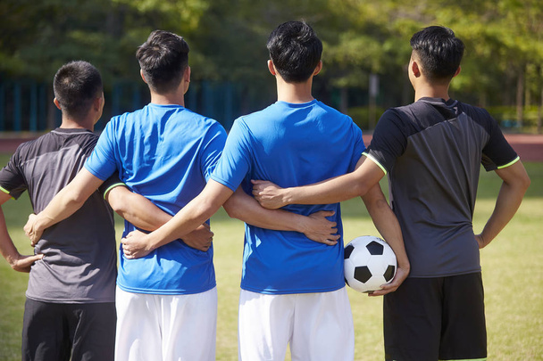 outdoor portrait of a team of young asian soccer football players, rear view - Foto, Imagem