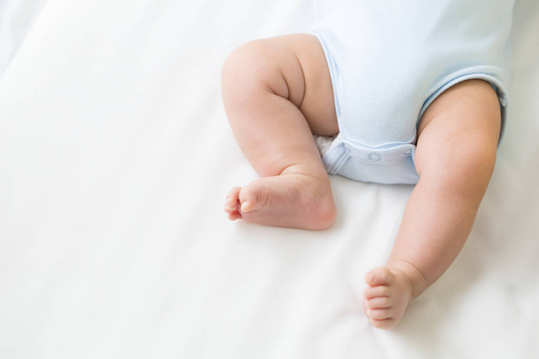 白いベッドの上に横になっている赤ちゃんの足 - 写真・画像