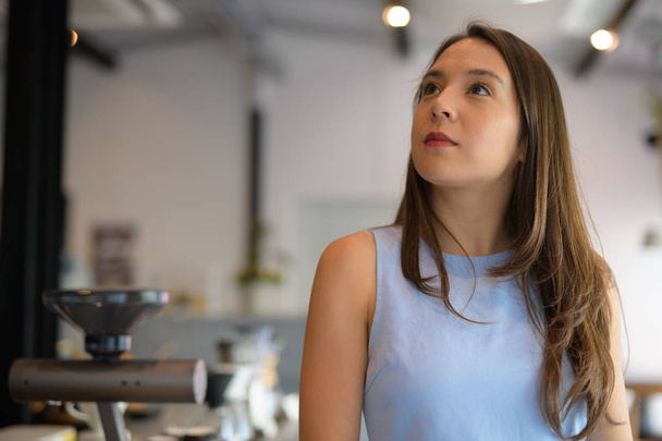 Joven hermosa mujer de negocios multiétnica pensando mientras mira hacia arriba en la cafetería
 - Foto, Imagen