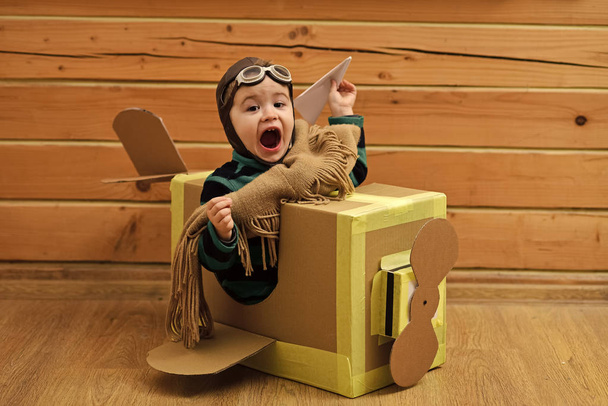 Child is flying on hand made cardboard plane. - Foto, afbeelding