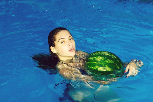 woman with watermelon in swimming pool - Foto, afbeelding