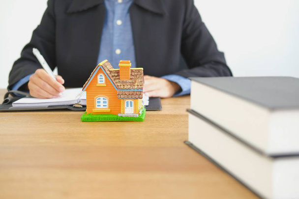 Immobilienmakler Makler Schreiben Notiz mit Hausmodell. Kauf, Verkauf und Vermietung von Immobilien - Foto, Bild