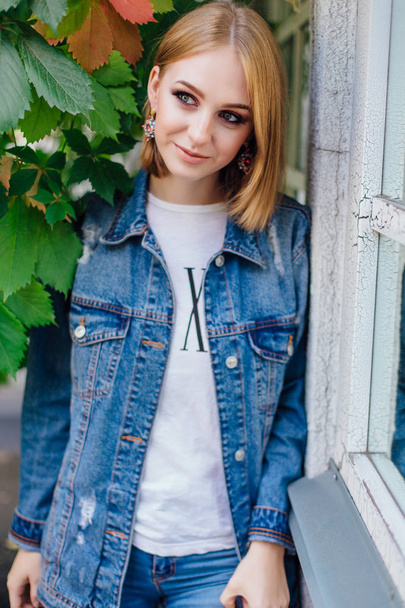 Fashion girl standing outdoors in denim oversized jacket and beautiful ear rings. - Foto, Imagem
