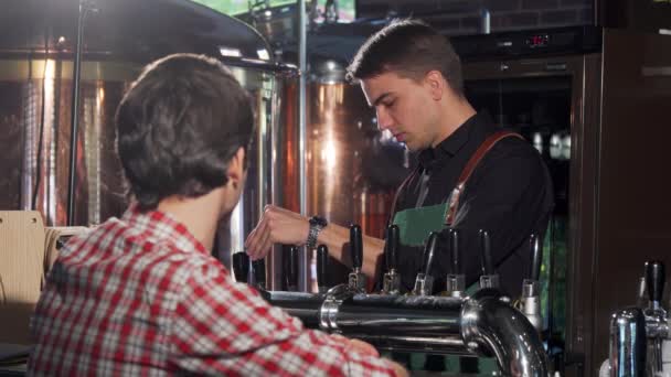 Wesoły barman leje piwo dla jego klienta - Materiał filmowy, wideo