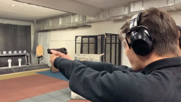El hombre apunta, sosteniendo un arma en una galería de tiro, campo de tiro. Mid shot
 - Metraje, vídeo