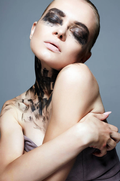 Beautiful Young woman with Paint Face. Halloween style dirty makeup Girl in Black Paint - 写真・画像