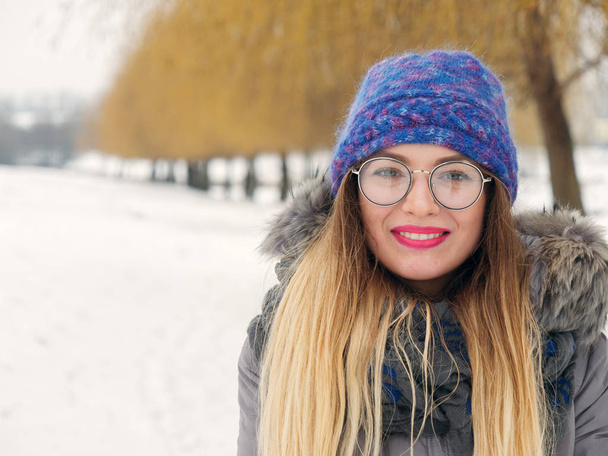 Красива щаслива дівчина в холоді в синьому капелюсі і круглих окулярах
 - Фото, зображення