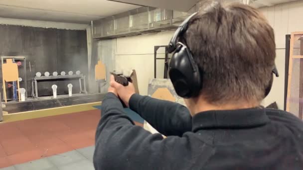 Молодий чоловік націлений, тримаючи пістолет у знімальній галереї, стріляючи в діапазон. Середній постріл
 - Кадри, відео