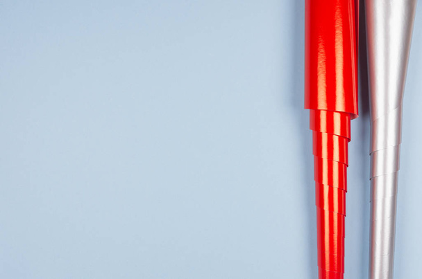 Modèle festif pour la conception et le texte de rouleaux de papier d'emballage rouge brillant et argent métallique sur fond bleu pastel, vue du dessus, espace de copie
. - Photo, image