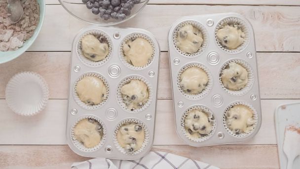 Scooping blueberry muffin batter into metal muffin pan. - Fotó, kép