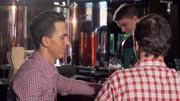 Pohledný muž cinkání sklenic se svým přítelem, těší, pití piva s přítelem - Záběry, video