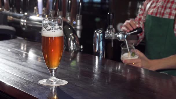 Vynikající řemeslné pivo na stole, barman pracuje na pozadí - Záběry, video