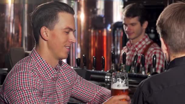 Przystojny szczęśliwy człowiek, pysznego piwa, mówiąc do przyjaciela w pubie - Materiał filmowy, wideo