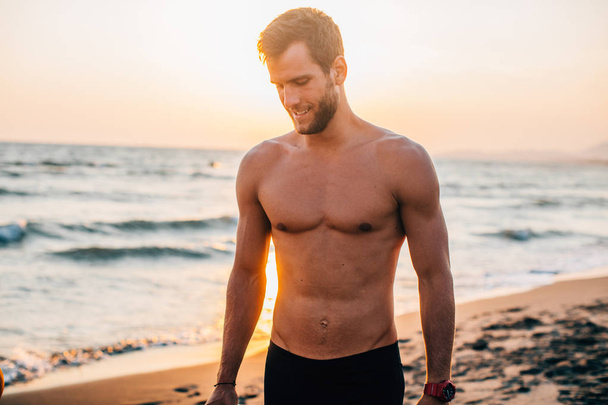 Portrait of handsome sportsman standing on beach. - Zdjęcie, obraz