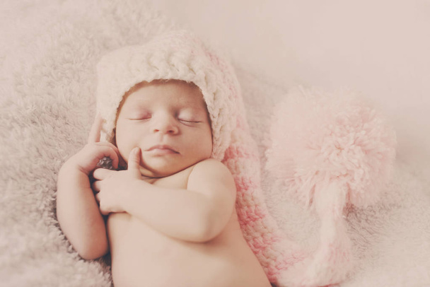 Милый маленький новорожденный ребенок носит розовую шляпу помпона
 - Фото, изображение
