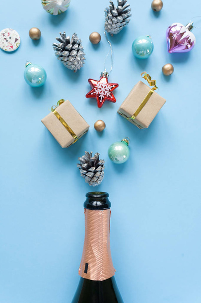 Champagne bottle with different christmas decoration on blue background. Open champagne concept. Flat lay. - Photo, Image