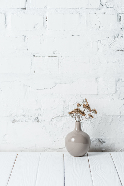 bouquet of dried flowers in ceramic vase near white brick wall - Foto, Imagem