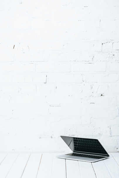 ноутбук на білому дерев'яному столі біля цегляної стіни
 - Фото, зображення