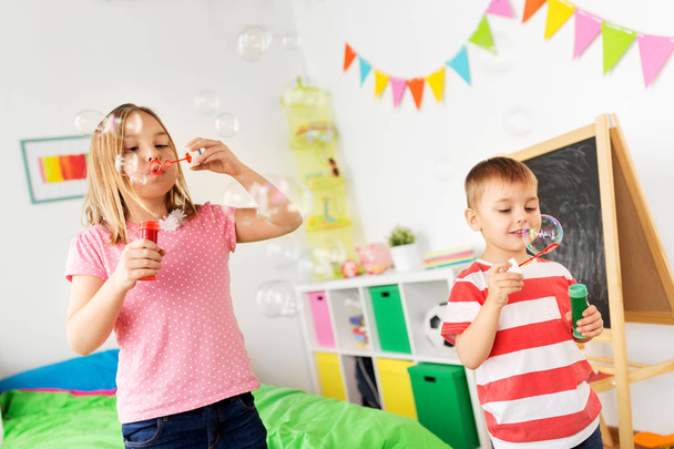 happy children blowing soap bubbles at home - Фото, изображение
