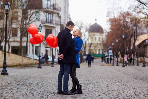 A loving couple in a coat with balloons hearts in hands.  - Photo, image