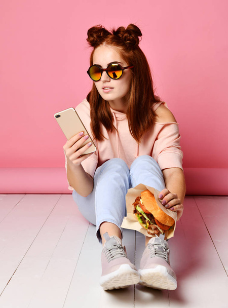 Vakava nuori nainen trendikkäissä silmälaseissa keskittyi puhelimen katseluun
 - Valokuva, kuva