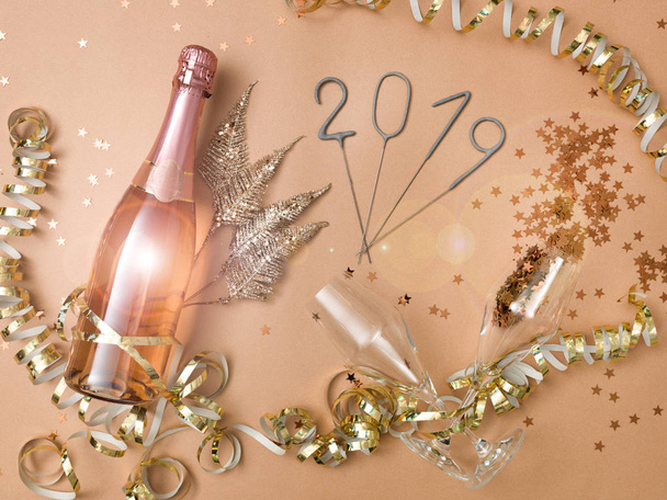новогодняя композиция бутылки шампанского и бокалов с новогодними экспонатами на бронзовом фоне
 - Фото, изображение