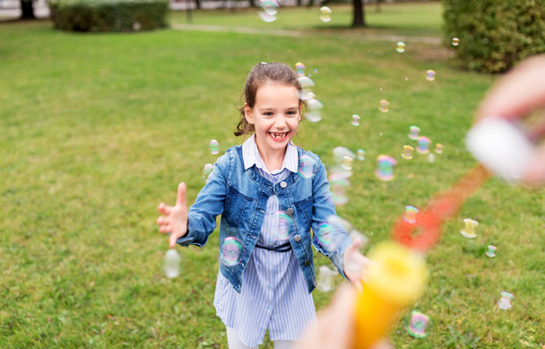 happy girl playing with soap bubbles at park - Fotoğraf, Görsel