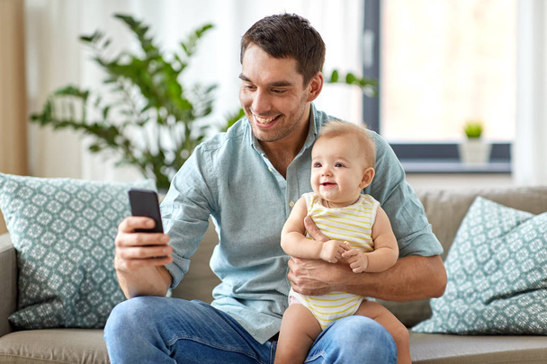 father with baby daughter using smartphone at home - Foto, Imagem