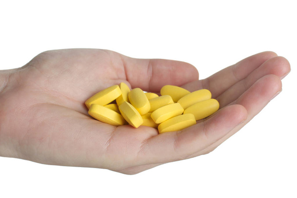 Żółty witamin w palmy na białym tle. Pojęcie zdrowia. - Zdjęcie, obraz