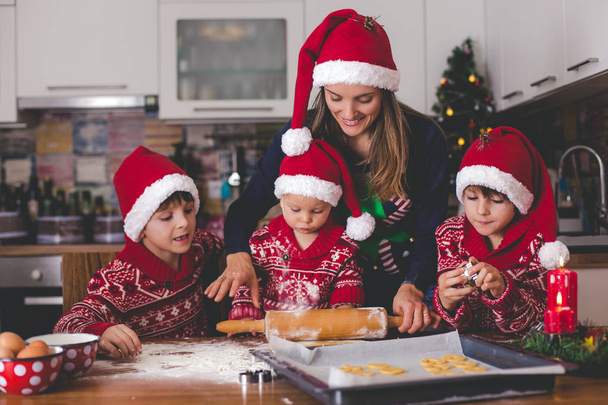 Sweet toddler child and his older brother, boys, helping mommy preparing Christmas cookies at home in kitchen - Foto, imagen