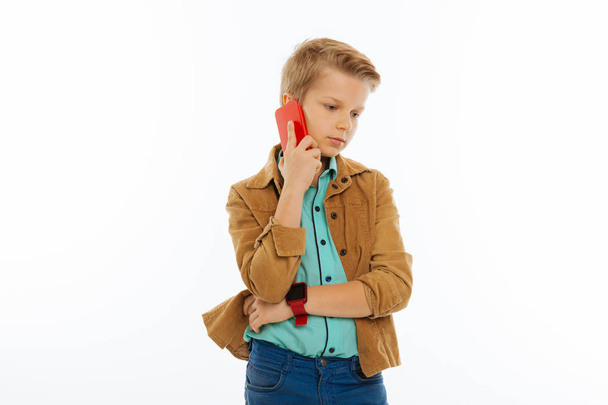 Serious cute boy answering the phone call - Foto, imagen