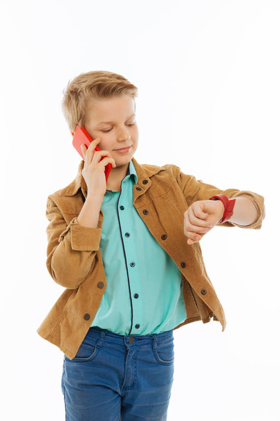Delighted positive boy looking at his watch - Фото, изображение