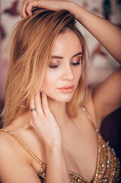Closeup portrait of sexy blonde woman looking down. Young beautiful girl with professional makeup, clean skin and shiny Golden dress. Fashion, glamour, luxury, party concept - Foto, imagen