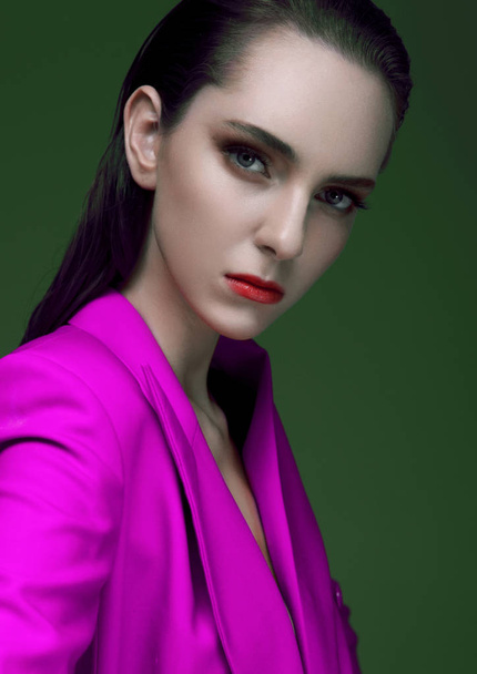 Fashion model with wet hair wearing violet purple long coat on green background. Fashion portrait. - Valokuva, kuva