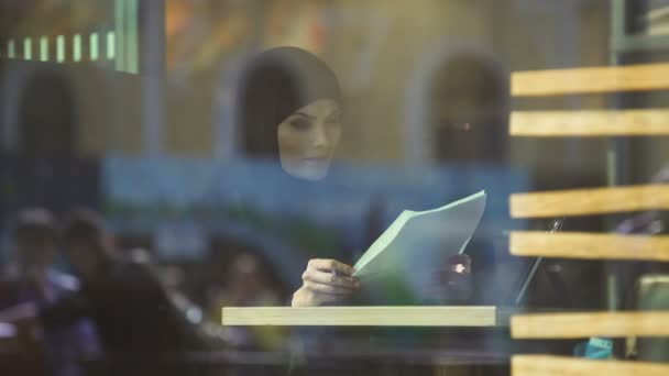 Pewna siebie arabski biznes Pani w café patrząc przez dokumenty, wolność - Materiał filmowy, wideo
