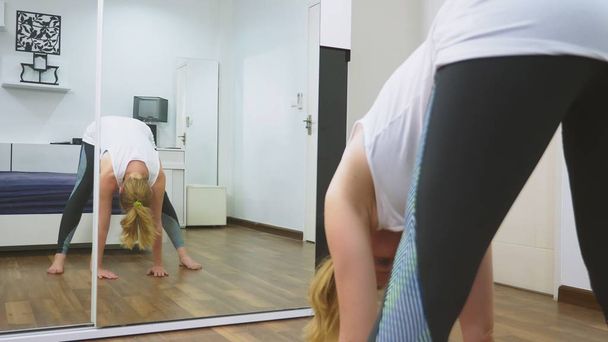 woman stretching near mirror at her apartment. The concept of a healthy lifestyle, not a professional sport. - Foto, imagen