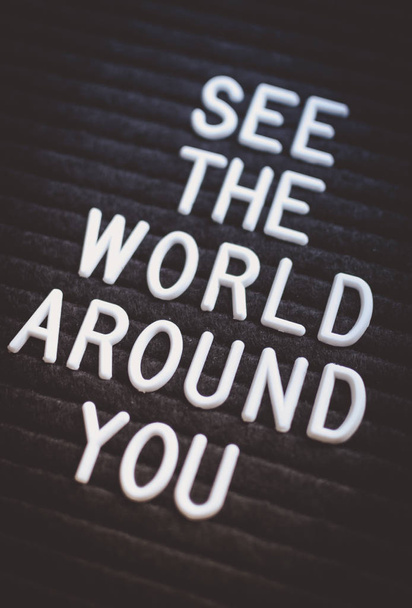 Phrase voir le monde autour de vous écrit sur le babillard. Lettres blanches sur le fond noir. Concept d'entreprise
 - Photo, image