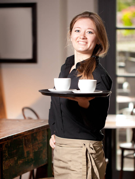 Portrait of waitress holding tray of coffee cups in cafe - Photo, Image
