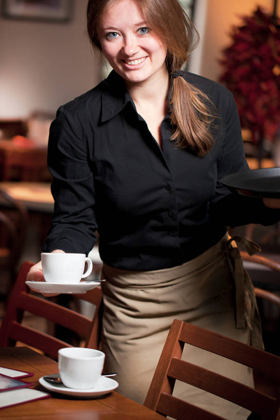 Portrait of waitress holding tray of coffee cups in cafe - Fotoğraf, Görsel