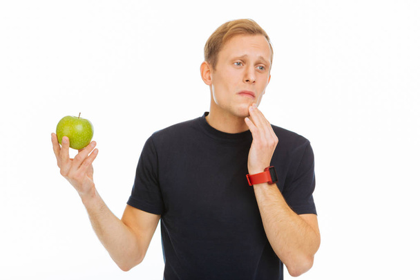 Pleasant sad man holding a green apple - Φωτογραφία, εικόνα